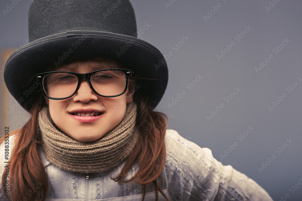 Young girl wearing top hat, glasses and scarf making funny face