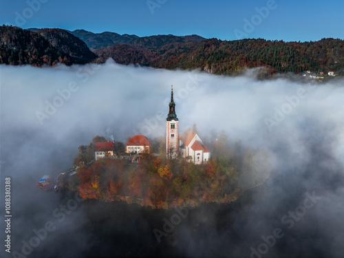 Obraz na płótnie Bled, Slovenia - Beautiful foggy autumn sunrise at Lake Bled with the famous Pilgrimage Church of the Assumption of Maria (Bled Island) covered in fog on an October morning. Clear blue sky w salonie