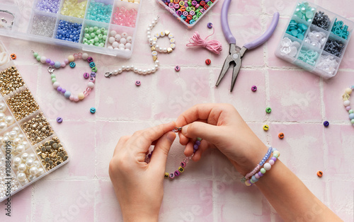Obraz na płótnie Child making beaded bracelets at home on pink tiled table w salonie