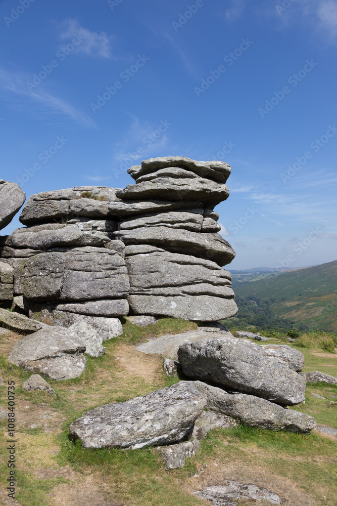 Tor or standing rocks on Dartmoor, Devon UK. Bright blue sky with strong sunlight and light clouds Tor or standing rocks on Dartmoor, Devon UK. Bright blue sky with strong sunlight and light clouds