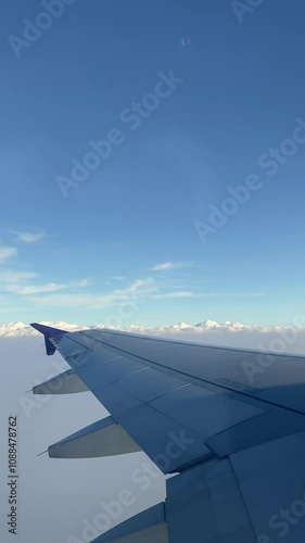 4k real time footage of airplane flight looking out from plane window. Vertical footage view from the window 
with silver wing of the airplane.