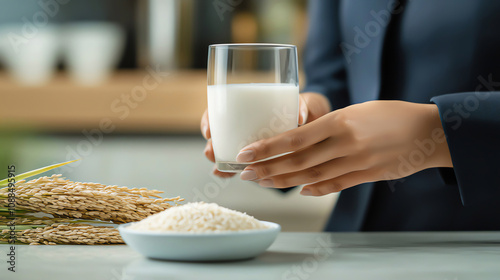 A working woman holds a glass of rice milk beside a bowl of rice and some rice stalks, highlighting wellbeing with plant based food concept photo