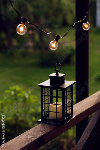evening summer garden, wooden porch decorated with light bulbs and candle light