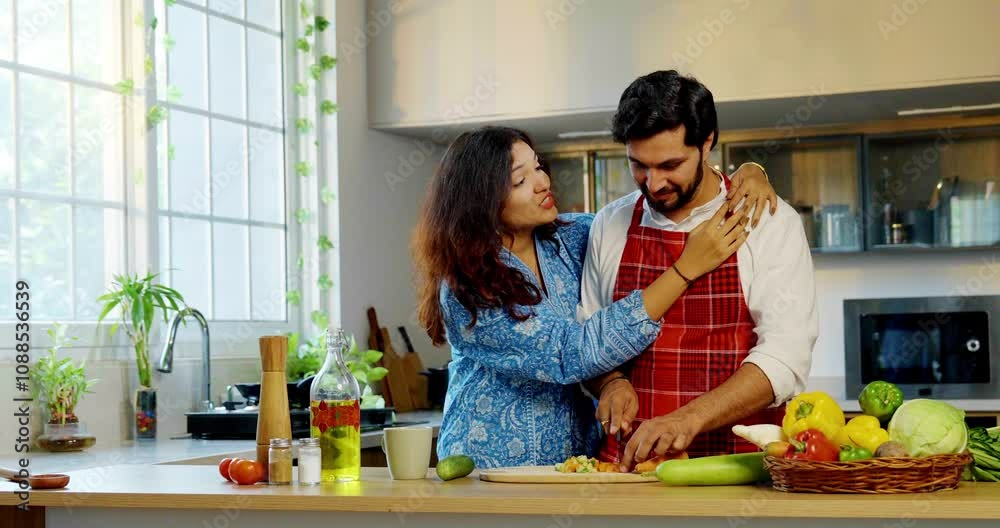 Indian Asian couple in the kitchen, young wife and husband chopping ...