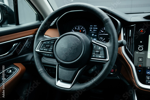 Modern brown car interior, leather steering wheel, climate control, large navigation screen, air ducts, deflectors on the car panel. Interior details. photo