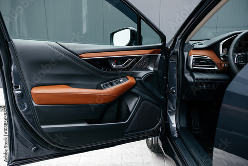 Modern brown car interior, leather steering wheel, climate control, large navigation screen, air ducts, deflectors on the car panel. Interior details.