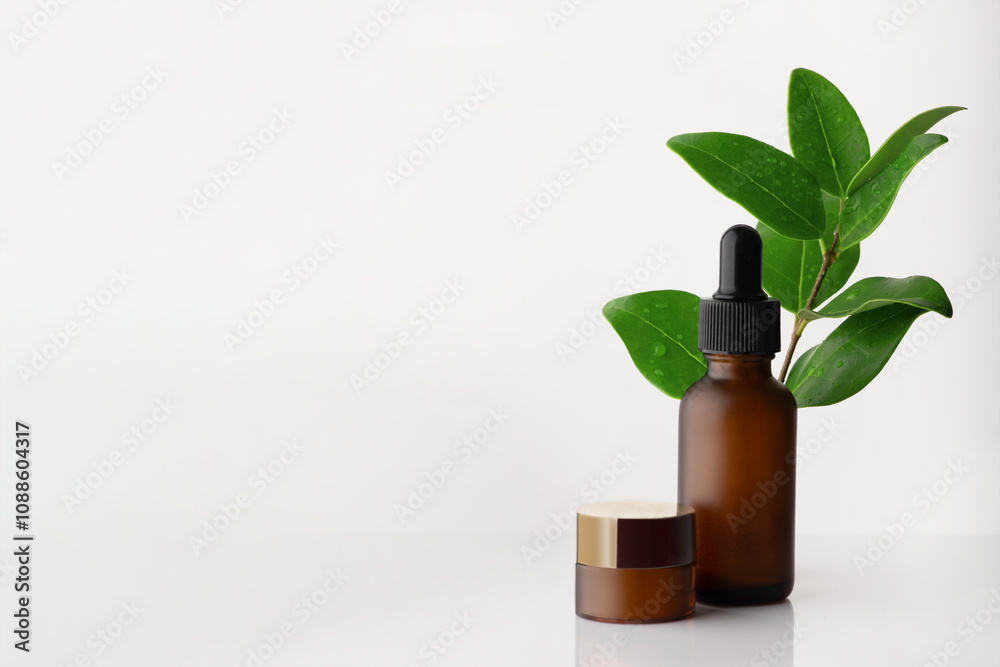 Dark glass bottle and cream, cosmetic products. In the background is a branch with leaves. Selective focus, copy space Dark glass bottle and cream, cosmetic products. In the background is a branch with leaves. Selective focus, copy space