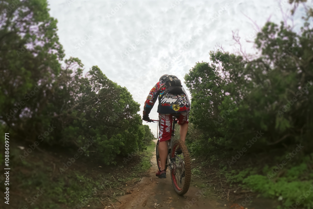 Naklejka premium Cyclist Riding the Bike on the Dirt Road.