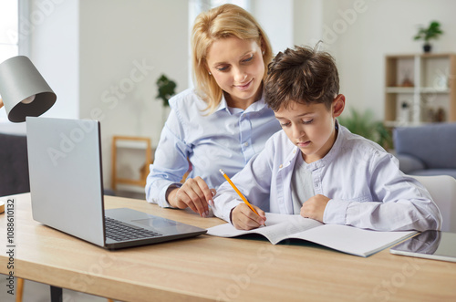 Loving family mother help, caring woman with little son together, writing notes at copy book, lesson, learning homework at home, education at laptop during online lecture, class, studying on Internet