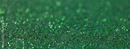 Blurred green sparkling background from sequins, macro. Shiny emerald glittery bokeh of christmas garland photo