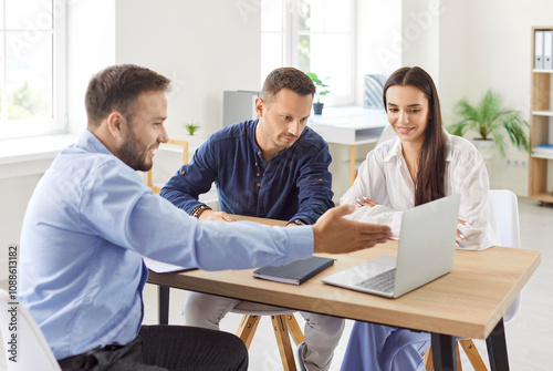 Couple of clients are engaged in conversation with a consultant or agent during an office briefing, using a laptop. Meeting focuses on investment strategies and decisions, providing essential advice.. photo