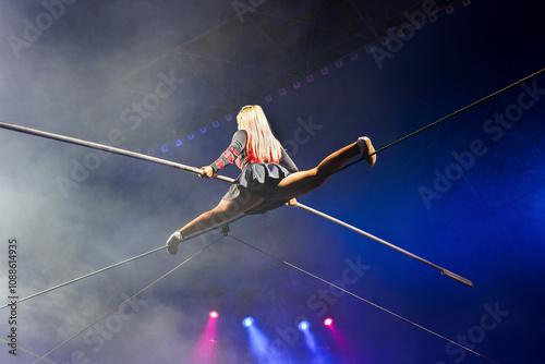 Bild auf Leinwand An acrobat girl sits on a rope stretched under the dome of the circus
