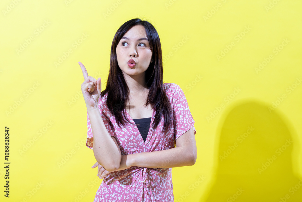 Indonesian Asian woman in a pink floral dress, smiling brightly against a yellow background. Bright, even lighting.