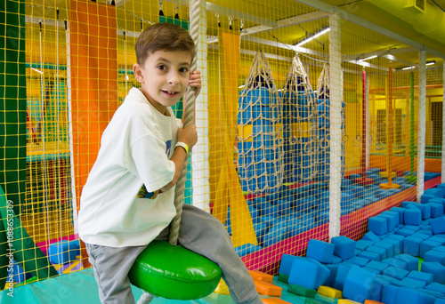 Cute cheerful boy playing from in entertainment center. photo