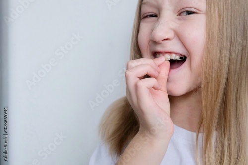 A dental plate for children of rainbow color. The child holds orthodontic braces in his hands to align the teeth and expand the jaw.