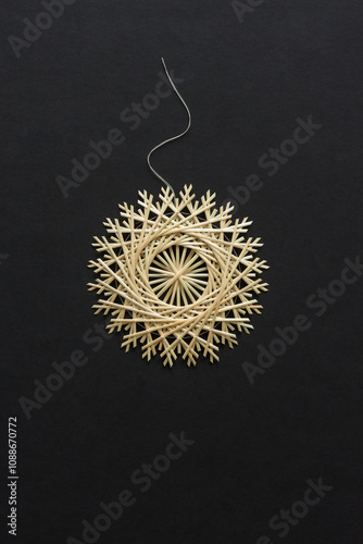 Snowflakes are made of straw on a black background. Straw star. Christmas decor. Top view. Straw weaving. Lutsk, Ukraine