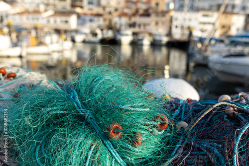 Fishing nets in the foreground with traditional fishing boats in the background at the port of Ciutadella in Menorca, Spain