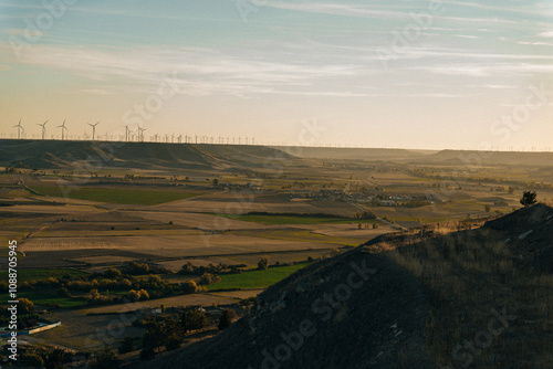 Andalusian agricultural landscape with hills, olive trees, blue sky and wind turbines. Agricultural area of Spain in Andalusia.