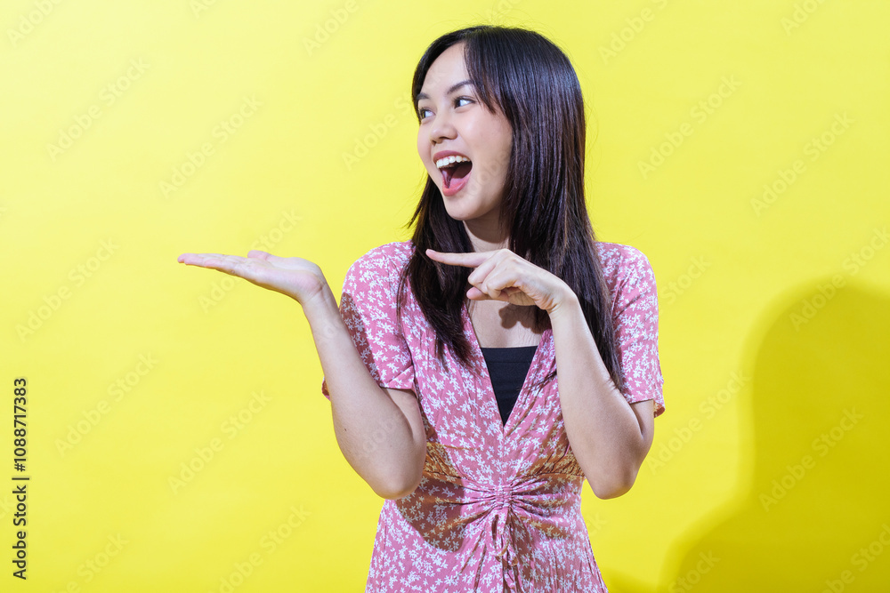 Indonesian Asian woman in a pink floral dress, smiling brightly against a yellow background. Bright, even lighting. Indonesian Asian woman in a pink floral dress, smiling brightly against a yellow background. Bright, even lighting.