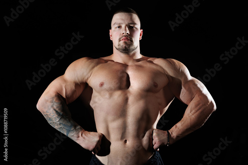 Muscular man showing muscles, isolated on the black background. Bodybuilder male naked torso abs.