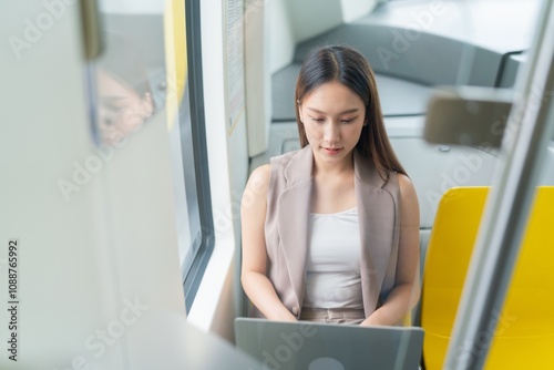 Asian Woman Using Laptop While Commuting in A Skytrain 