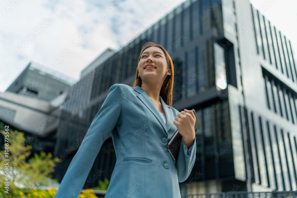 Fototapeta premium Young Businesswoman Using Digital Tablet In Front A Modern Office Building in a Financial District