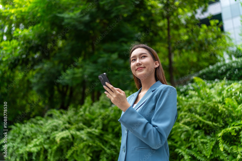 Young Businesswoman In Blue Suit Using Phone Amid Greenery of A Park In The City Young Businesswoman In Blue Suit Using Phone Amid Greenery of A Park In The City
