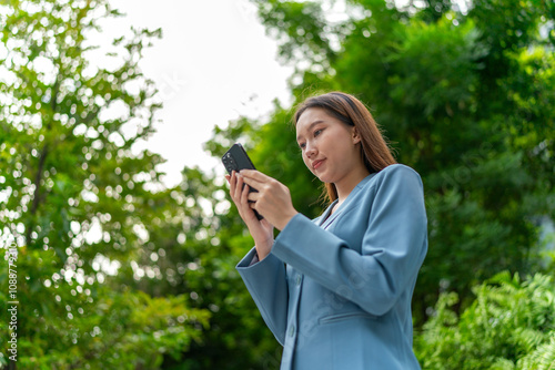 Young Businesswoman In Blue Suit Using Phone Amid Greenery of A Park In The City