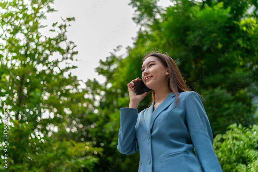 Young Businesswoman In Blue Suit Using Phone Amid Greenery of A Park In The City Young Businesswoman In Blue Suit Using Phone Amid Greenery of A Park In The City