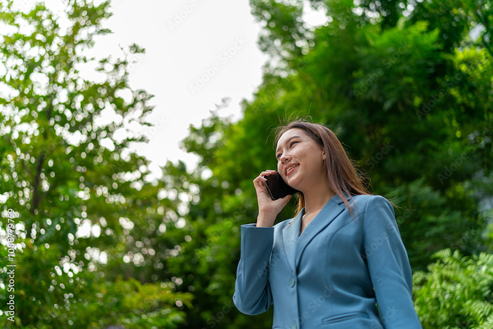 Young Businesswoman In Blue Suit Using Phone Amid Greenery of A Park In The City Young Businesswoman In Blue Suit Using Phone Amid Greenery of A Park In The City