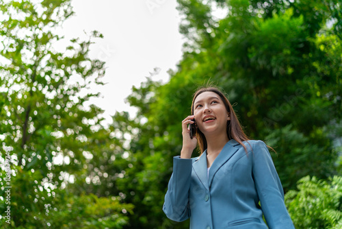 Young Businesswoman In Blue Suit Using Phone Amid Greenery of A Park In The City