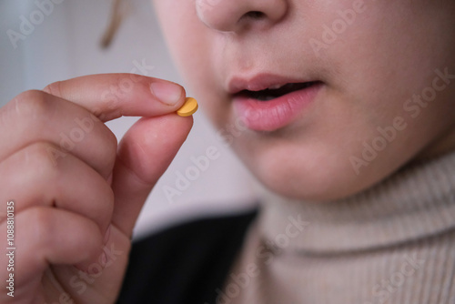 Close up image of a girl  taking white round pill. Young girl taking medicines, antidepressant.