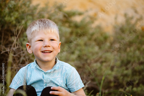 Caucasian boy overjoyed while sitting with vegetation in the background in Albufeira, Portugal photo