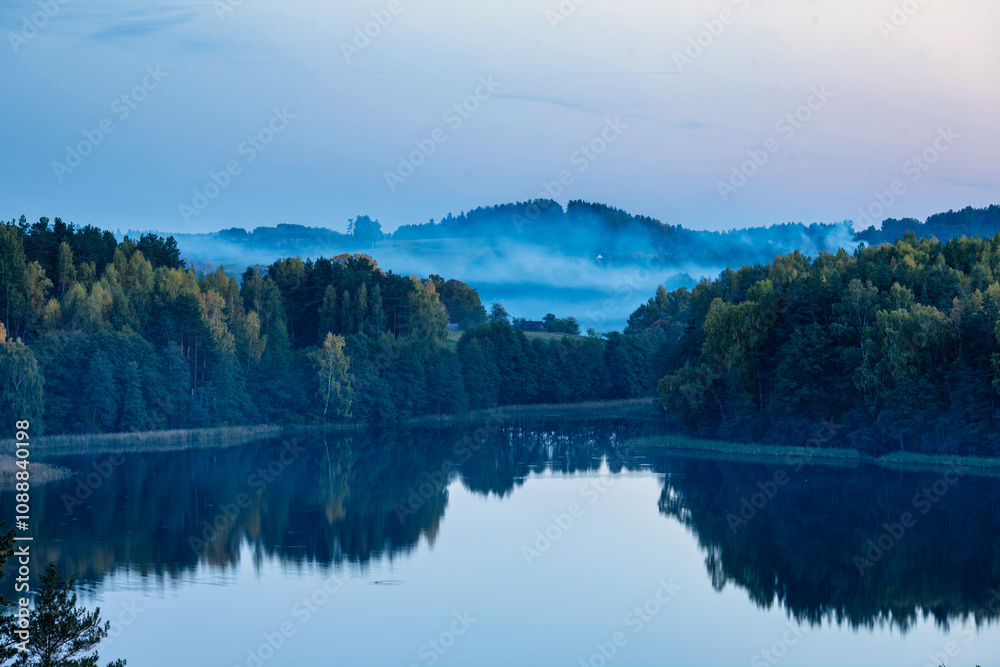 Fototapeta premium Misty Morning Reflections Over a Serene Forest Lake 