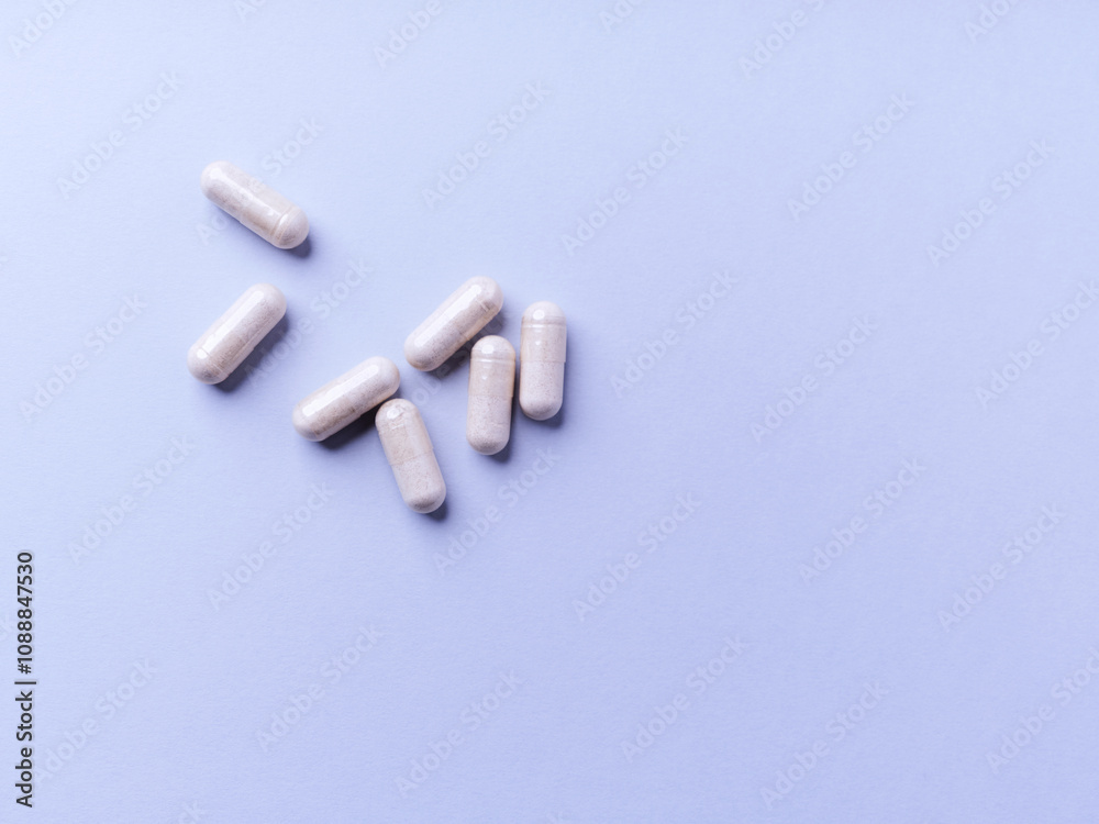 Obraz premium Creatine capsules on bright paper background. Soft focus. Close up. Copy space.