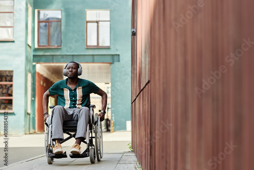 Foto Full length portrait of young African American man with disability using wheelch