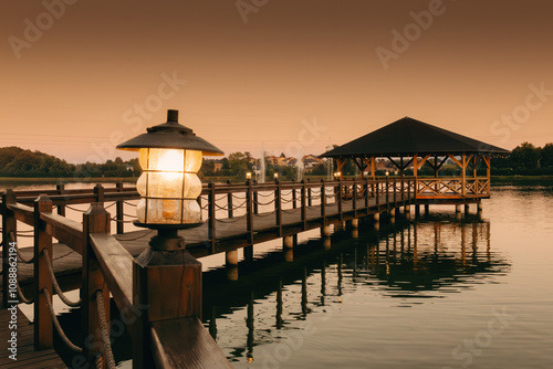 Fototapeta Naklejka Na Ścianę i Meble -  Sunset on the lake with a pier and a house on the water, architecture on the pond, lakes in Poland, recreation places