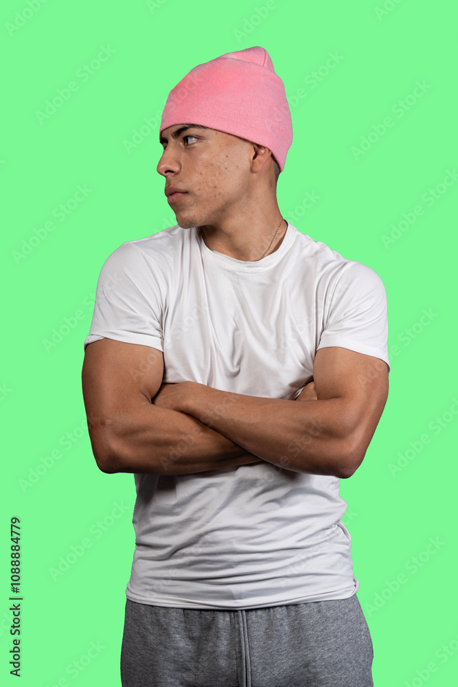 Young latino man wearing pink beanie and crossing arms on green background Young latino man wearing pink beanie and crossing arms on green background