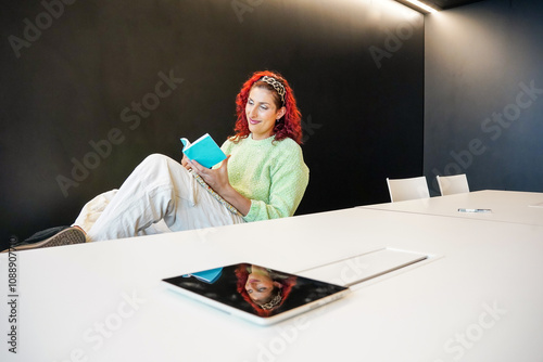 Trans woman reading book in modern office setting photo