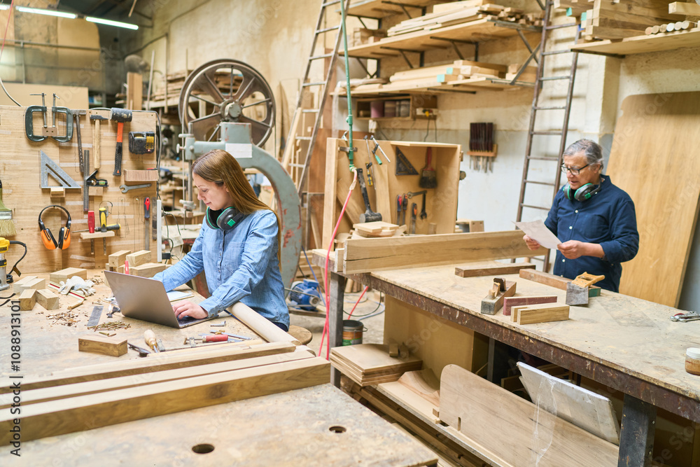 Young apprentice working alongside mentor in a busy lumberyard Young apprentice working alongside mentor in a busy lumberyard