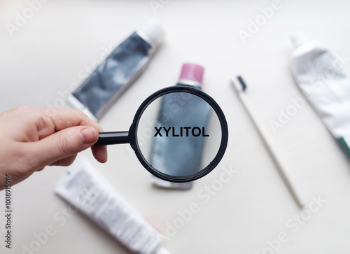 Xylitol in natural toothpaste. Magnifying glass is directed at a tube with a list of ingredients of a safe product. Safe toothpaste composition photo