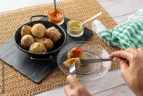 A rustic black dish of papas arrugadas, a traditional Canarian dish, elegantly arranged and garnished with coarse salt, served with vibrant red and green sauces. photo