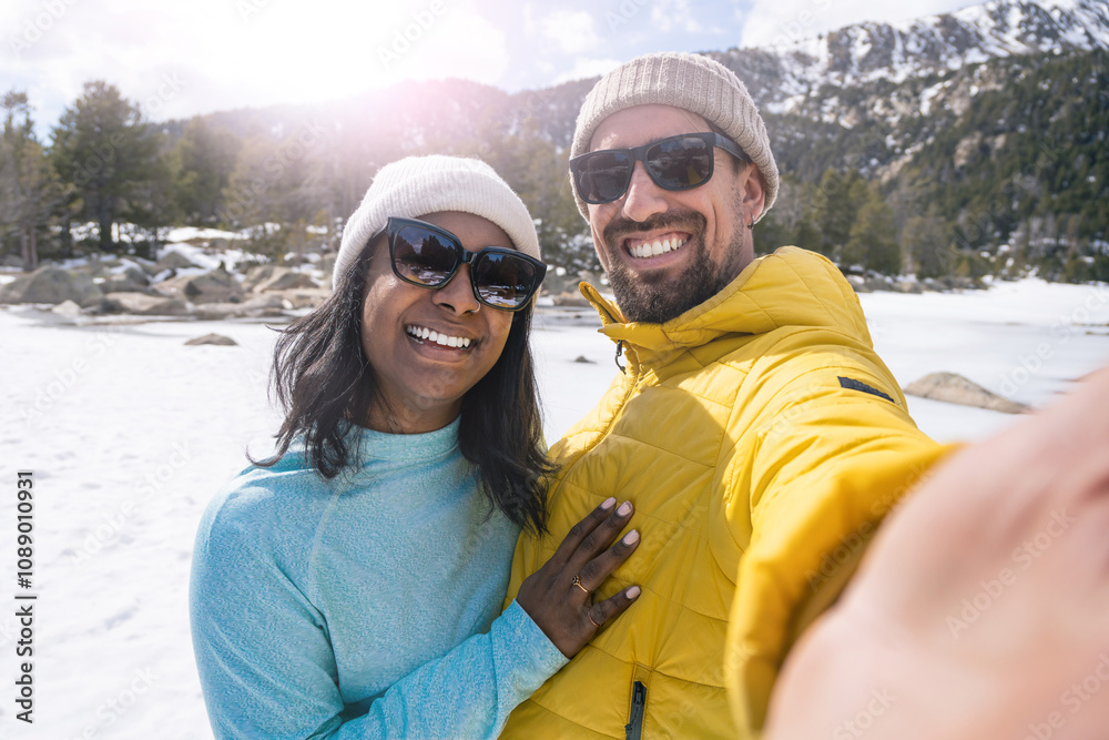 Young cheerful multiracial couple taking selfie photo in the snow trip in winter Young cheerful multiracial couple taking selfie photo in the snow trip in winter