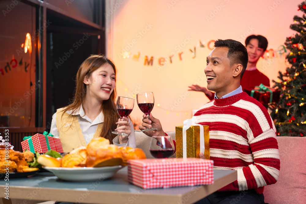 Two handsome men and two beautiful women laugh joyfully while celebrating Christmas. They enjoy delicious food, drinks, exchange gifts in a lively atmosphere, creating unforgettable festive memories Two handsome men and two beautiful women laugh joyfully while celebrating Christmas. They enjoy delicious food, drinks, exchange gifts in a lively atmosphere, creating unforgettable festive memories