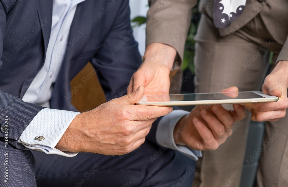 Close-up of co-workers standing at desk with laptop and talking