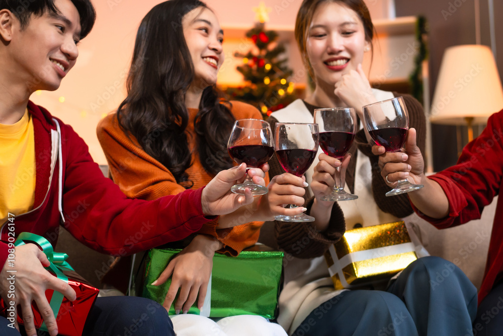 Two handsome young men and two beautiful young women wearing Christmas hats laughing joyfully at a Christmas party with delicious food, drinks and a cheerful exchange of thoughtful gifts Two handsome young men and two beautiful young women wearing Christmas hats laughing joyfully at a Christmas party with delicious food, drinks and a cheerful exchange of thoughtful gifts
