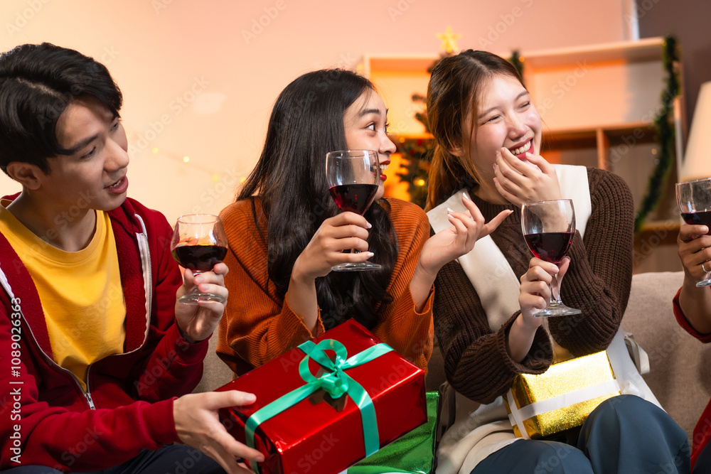 Two handsome young men and two beautiful young women wearing Christmas hats laughing joyfully at a Christmas party with delicious food, drinks and a cheerful exchange of thoughtful gifts Two handsome young men and two beautiful young women wearing Christmas hats laughing joyfully at a Christmas party with delicious food, drinks and a cheerful exchange of thoughtful gifts
