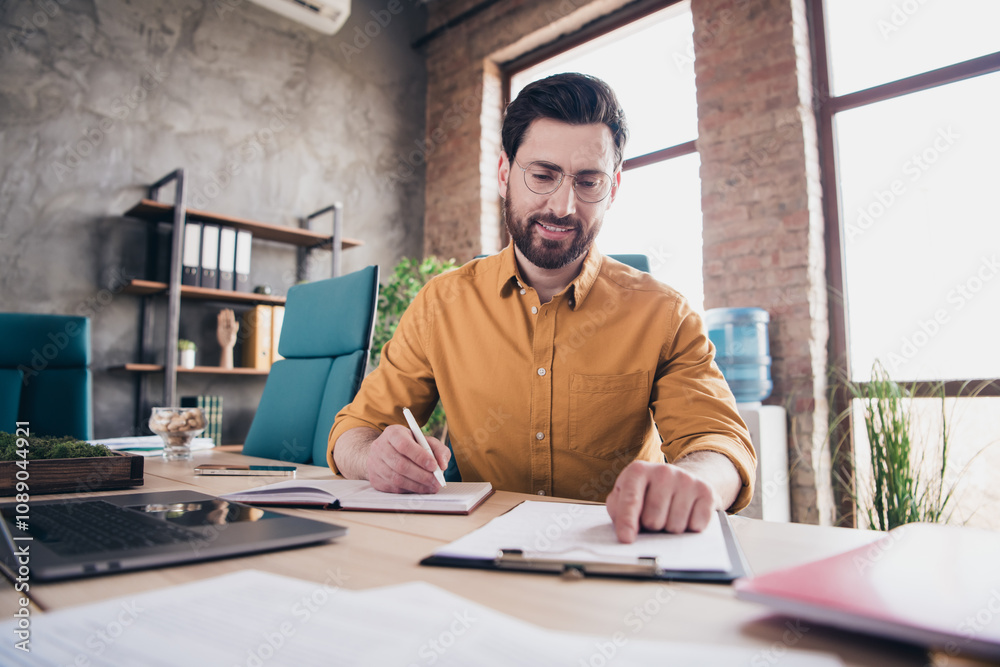 Photo of handsome young guy write documents report dressed yellow shirt formalwear comfortable startup office loft room interior Photo of handsome young guy write documents report dressed yellow shirt formalwear comfortable startup office loft room interior