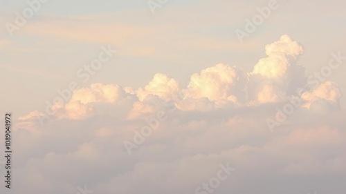 Softly glowing cumulus clouds in a gradient of pastel colors against a pale blue sky, forming a wispy veil in the distance, abstract, veiled, misty