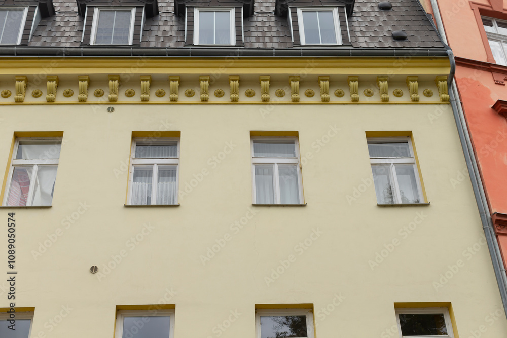 Obraz premium The facade of a beautifully designed yellow building showcases exquisite decorative architectural details and an array of multiple windows, enhancing the charm and character of the urban landscape
